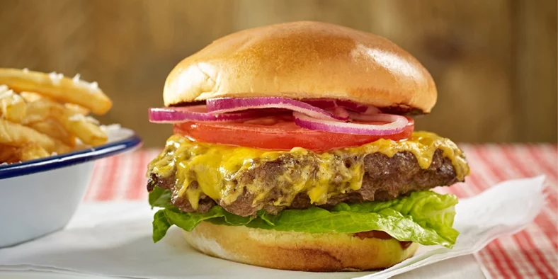 Fairway Assured burger in a bun with lettuce, tomatoes, red onion and melted cheese